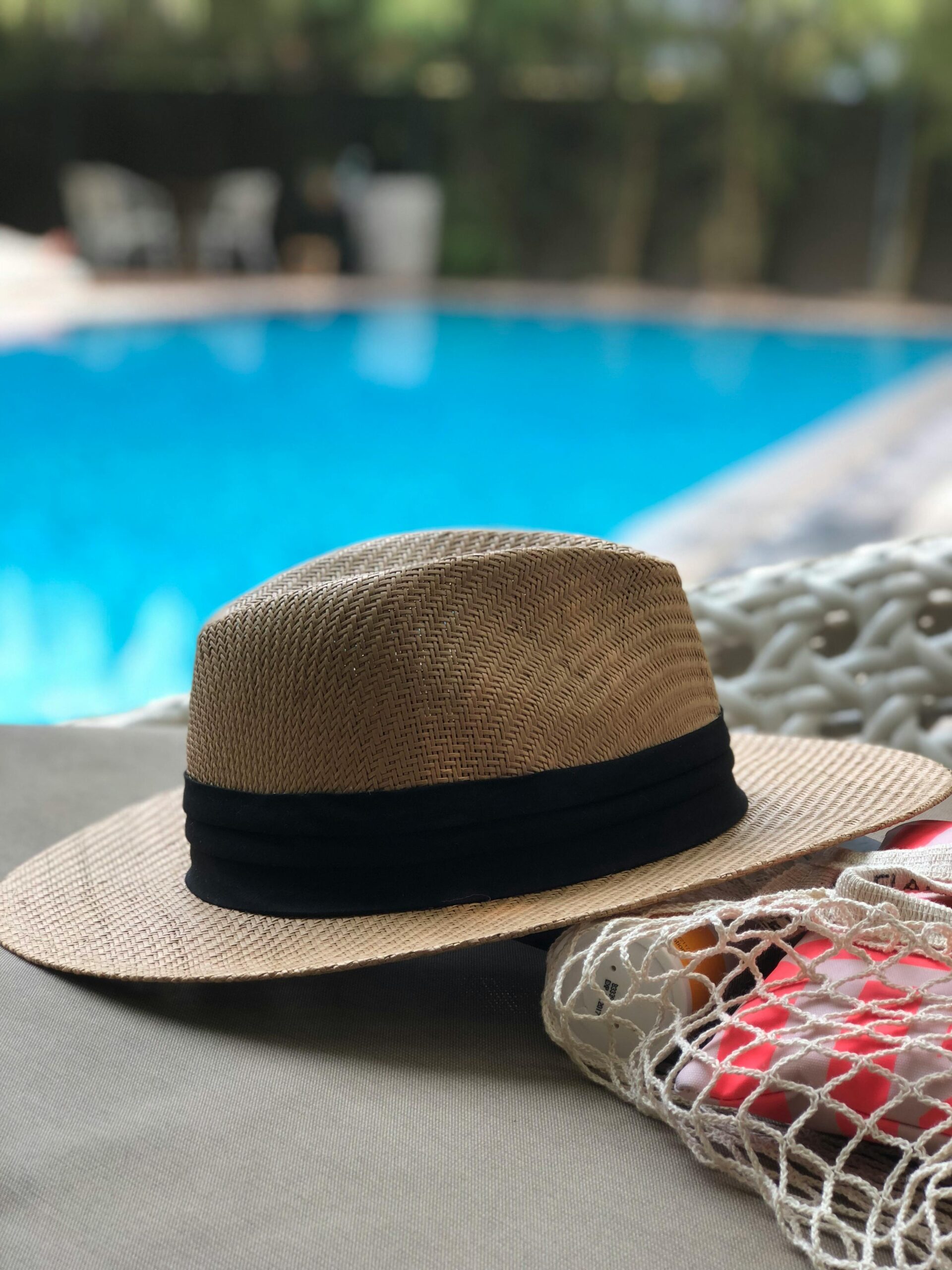 A stylish straw hat rests poolside, capturing a serene summer vibe.